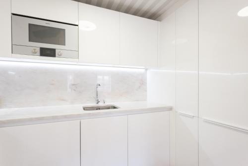 a white kitchen with a microwave above a sink at FLH Restauradores Amazing Flat with View in Lisbon
