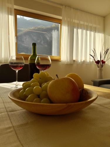 a bowl of fruit on a table with two glasses of wine at Versigglhof in Appiano sulla Strada del Vino