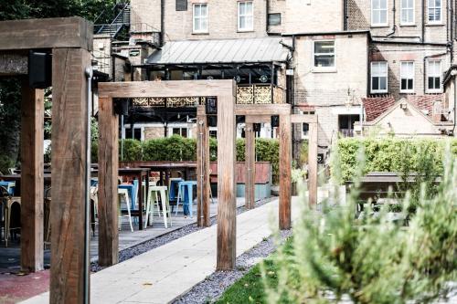 a wooden arch in a garden with tables and chairs at The Drayton Court Hotel in London