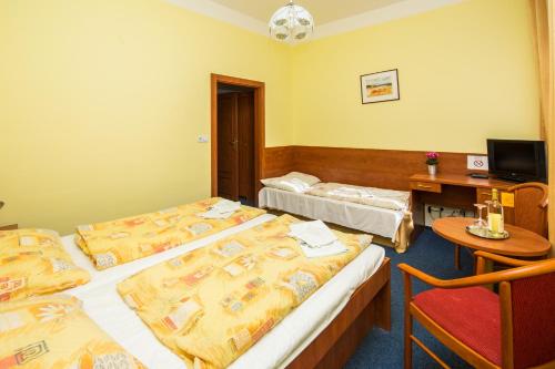 a hotel room with two beds and a desk with a computer at Hotel Morava in Znojmo