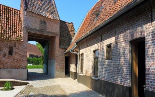 an alley between two brick buildings with an archway at B&B - La Cense du Pont in Bachy
