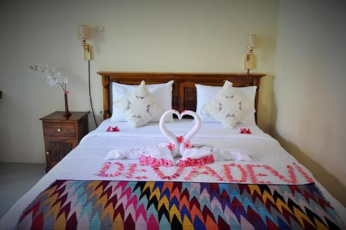 a bed with two white swans forming a heart at Deva Devi Beach Inn Luxury in Nusa Penida