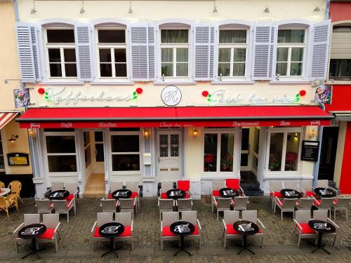 Un restaurante con mesas y sillas frente a un edificio. en Aparthotel C'est la vie, en Saarlouis