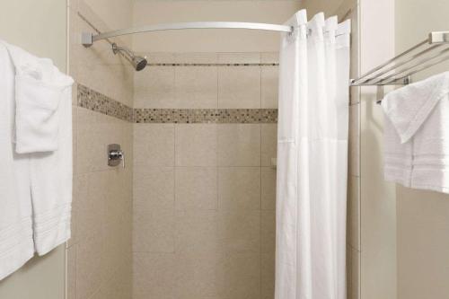 a shower with a white shower curtain in a bathroom at Travelodge by Wyndham Motel of St Cloud in Saint Cloud