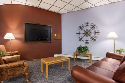 a waiting room with a couch and a tv at Travelodge by Wyndham Motel of St Cloud in Saint Cloud