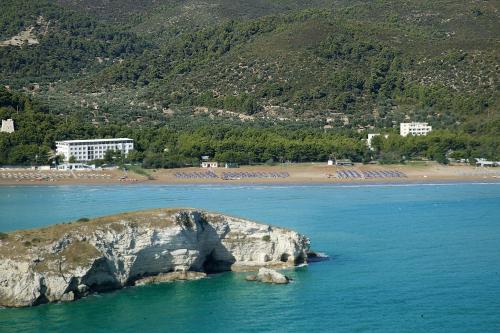 a rock in the water next to a beach at Hotel Portonuovo in Vieste