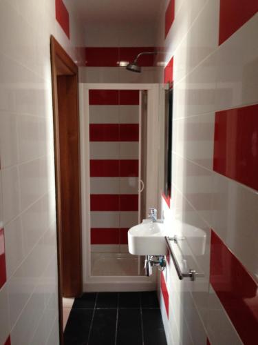 baño con lavabo y pared de rayas rojas y blancas en Joe Ann Apartments, en San Julián