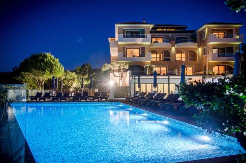 a swimming pool in front of a building at night at Kymothoe Elite Suites in Tsilivi