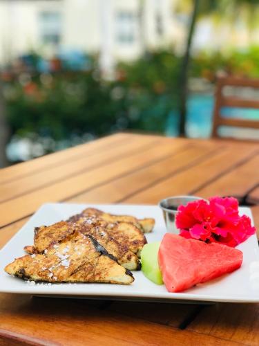 Een bord met eten, watermeloen en een bloem op tafel. bij Pelican Reef Villas Resort in San Pedro