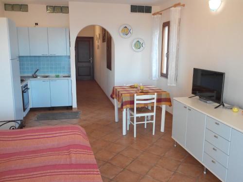kuchnia i jadalnia ze stołem i telewizorem w obiekcie Splendido mono vista mare con wi fi a 100 mt da spiaggia w mieście Santa Teresa Gallura