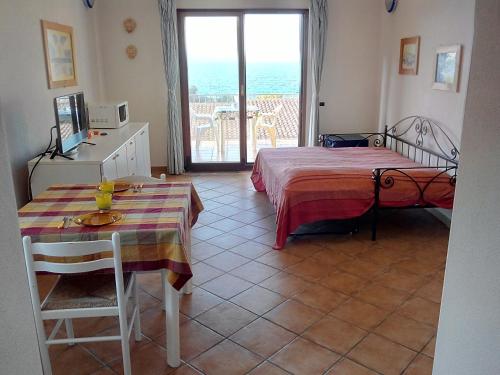 Pokój z łóżkiem, stołem i oknem w obiekcie Splendido mono vista mare con wi fi a 100 mt da spiaggia w mieście Santa Teresa Gallura