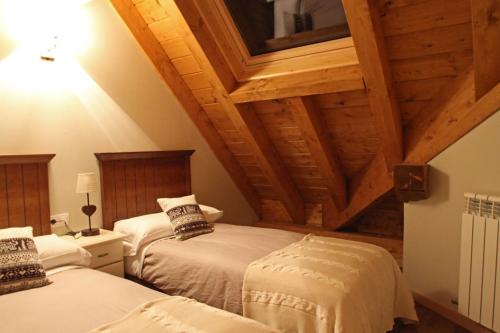 two beds in a room with wooden ceilings at Aparthotel Foratata in Sallent de Gállego