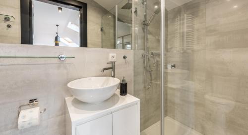 bagno con lavandino e doccia in vetro di Downtown Apartments Cracow a Cracovia