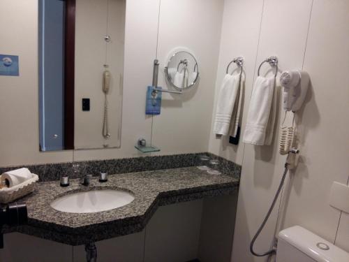a bathroom with a sink and a mirror and a phone at Metropolitan Hotel Brasília in Brasilia