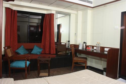 a hotel room with a desk and a table and chairs at Hotel Karl Residency in Mumbai