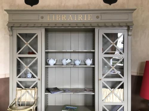Un armario con puertas de cristal y jarrones encima. en Hotel De La Loire, en Saint-Satur