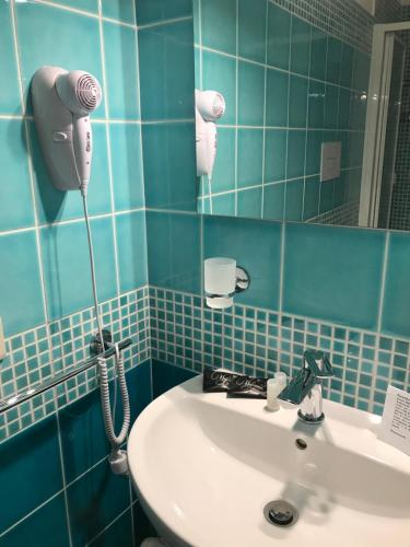 baño de azulejos azules con lavabo y secador de pelo en Good Night Moon B&B, en Crotone
