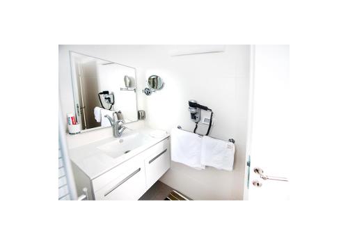 a white bathroom with a sink and a mirror at Boutique Apartment "Facing the Sea" in Haifa