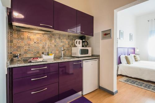a kitchen with purple cabinets and a bed in a room at Apartamento Purple Room in Porto