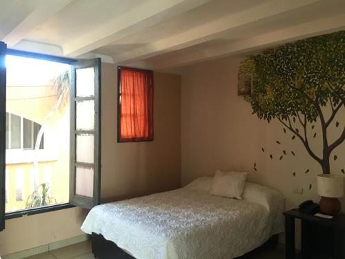 a bedroom with a bed and a tree on the wall at Hotel Calli Quetzalcoatl in Cholula