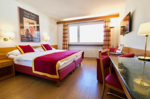 een hotelkamer met een groot bed en een bureau bij Hôtel du Rhône in Sion