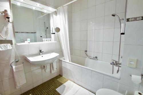 La salle de bains est pourvue d'un lavabo, d'une baignoire et de toilettes. dans l'établissement Hôtel du Rhône, à Sion