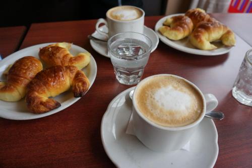 una mesa con dos platos de bollería y una taza de café en Hotel Paris en General San Martín