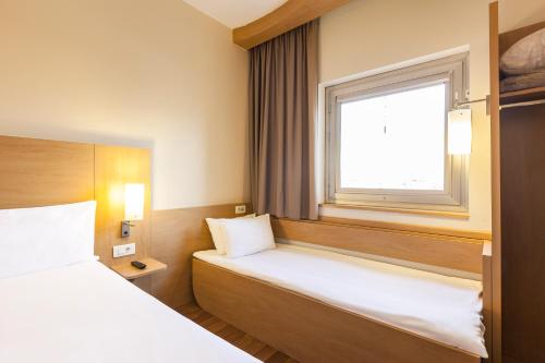 a small room with a bed and a window at ibis Santiago Providencia in Santiago