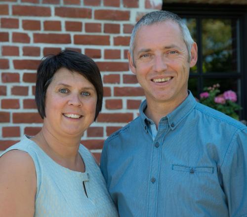 a man and a woman standing in front of a brick building at B&B de Rijcke Rust in Rijkevorsel