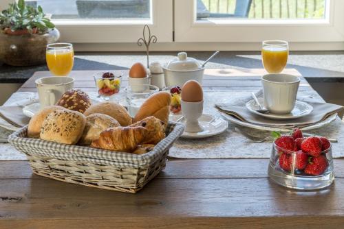 una mesa con una cesta de pan, huevos y fresas en B&B de Rijcke Rust, en Rijkevorsel