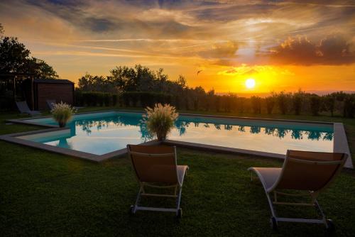basen z 2 krzesłami i zachodem słońca w tle w obiekcie Villa Degli Ulivi w mieście Viterbo