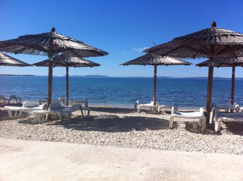 a group of chairs and umbrellas on a beach at Apartments Barbara 111 in Vir