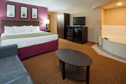 a hotel room with a bed and a table and a couch at AmericInn by Wyndham Osceola in Osceola