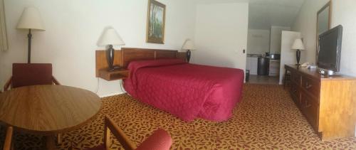 a hotel room with a red bed and a table at Western Inn Motel & RV Park in Fairplay