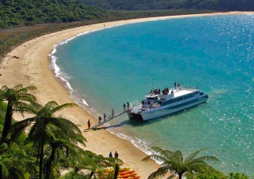 a boat in the water next to a beach at Awaroa Lodge in Awa-iti