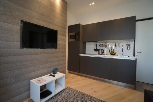 a kitchen with black cabinets and a flat screen tv at Carré d'OR! Park view! in Nice