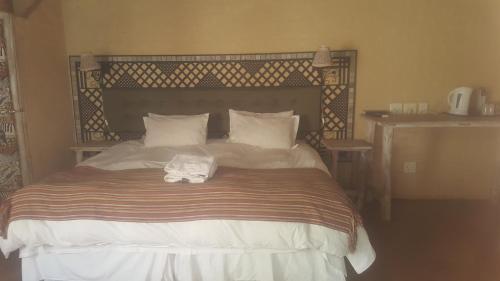 a bed in a bedroom with a bedvisor with a towel on it at African Silhouette Guesthouse in Benoni