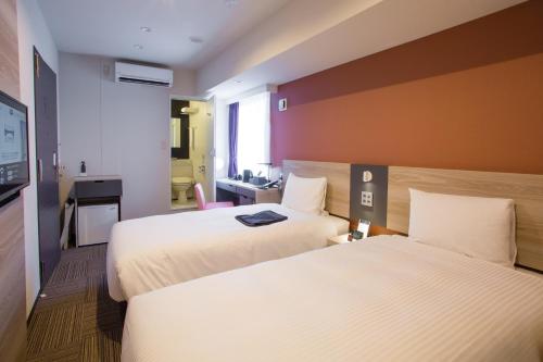 a hotel room with two beds and a television at Kuretake Inn Premium Nagoya Nayabashi in Nagoya