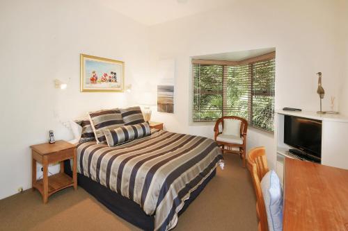 Schlafzimmer mit einem Bett, einem Schreibtisch und einem TV in der Unterkunft Alderly Apartment 10, Little Cove in Noosa Heads