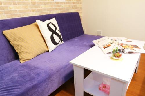 a purple couch with a pillow and a table at Chidori Inn Fukuromachi Hiroshima in Hiroshima