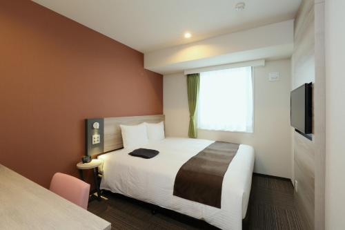 a hotel room with a bed and a window at Kuretake Inn Premium Nagoya Nayabashi in Nagoya