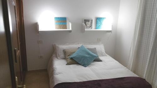 una cama blanca con almohadas en una habitación en Relaxing Atico Playa Sardina, en Gáldar