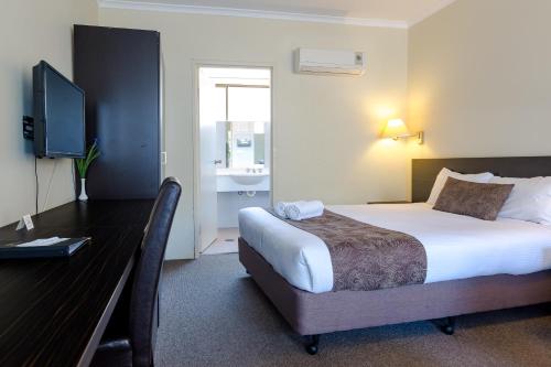 a bedroom with a bed and a desk with a television at Abcot Inn in Sylvania