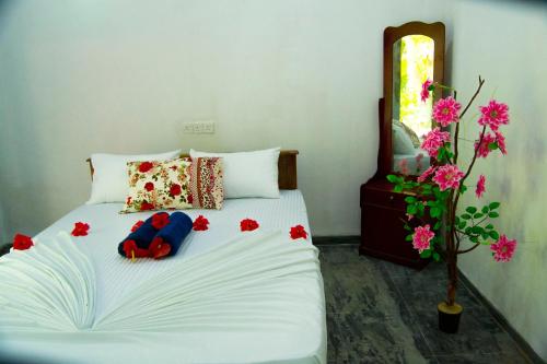 a bedroom with a white bed with flowers on it at Amba Sewana Homestay in Sigiriya