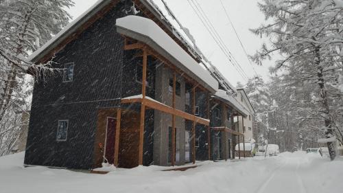 a building in the snow with snow on it at Kitsune Cottages in Hakuba