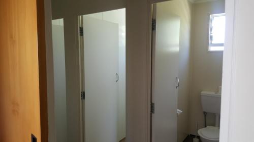 a bathroom with a toilet and a glass shower door at High Country Lodge, Motels & Backpackers in Twizel