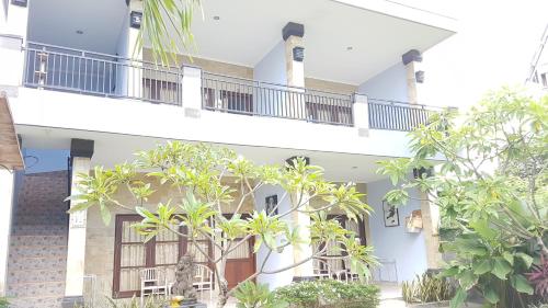 a white building with trees in front of it at Koming Guest House in Canggu