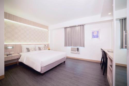 a bedroom with a large white bed and a desk at The Charter House in Manila