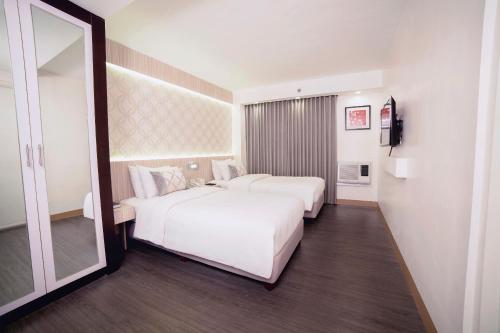 a hotel room with two beds and a mirror at The Charter House in Manila