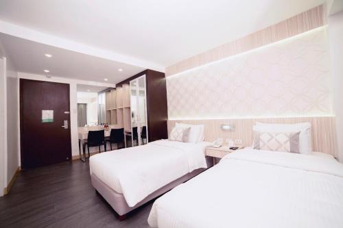 マニラにあるThe Charter Houseのベッド2台とテーブルが備わるホテルルームです。